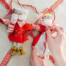 Kobieta własnoręcznie przygotowuje lalkę motankę. Folk(od)nowa