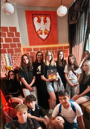 Uczniowie klasy 7 pozują do grupowego zdjęcia w pokoju zagadek